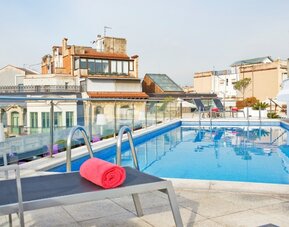 Rooftop swimming pool featuring sun loungers and surrounding city views at NH Collection Barcelona Pódium.