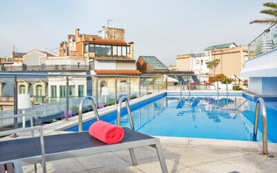 Rooftop swimming pool featuring sun loungers and surrounding city views at NH Collection Barcelona Pódium.