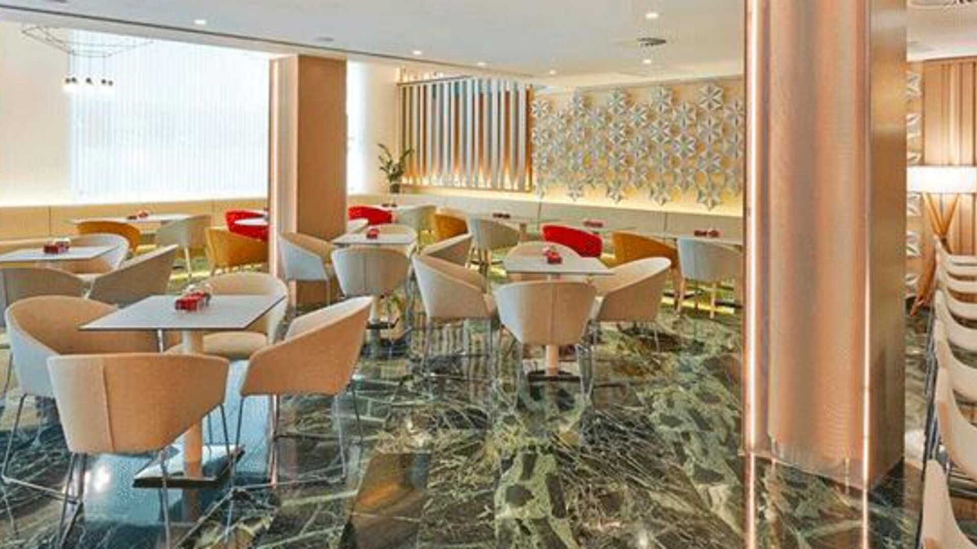 Modern dining area featuring tables, upholstered chairs and a bar counter at NH Collection Barcelona Pódium.