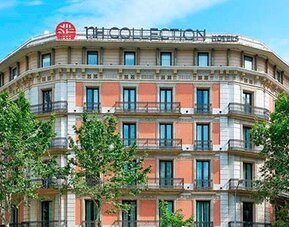 Exterior view of the historic building with balconies and surrounding trees at NH Collection Barcelona Pódium.