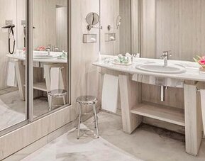 Spacious bathroom featuring a vanity, large mirrors, wall-mounted hairdryer and contemporary finishes at NH Collection Barcelona Pódium.