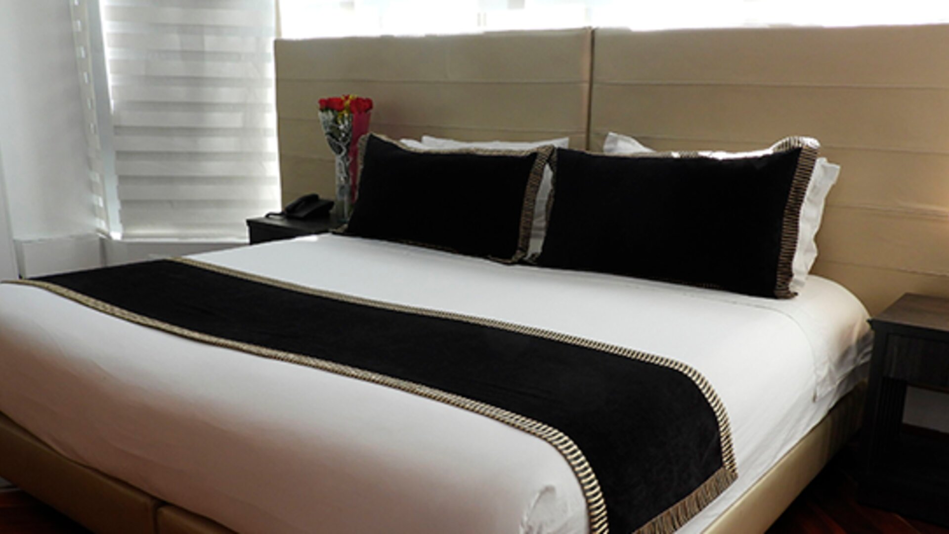 Guest room featuring a king bed, black accent cushions, bedside tables and contemporary lighting at Hotel Airport Travel.