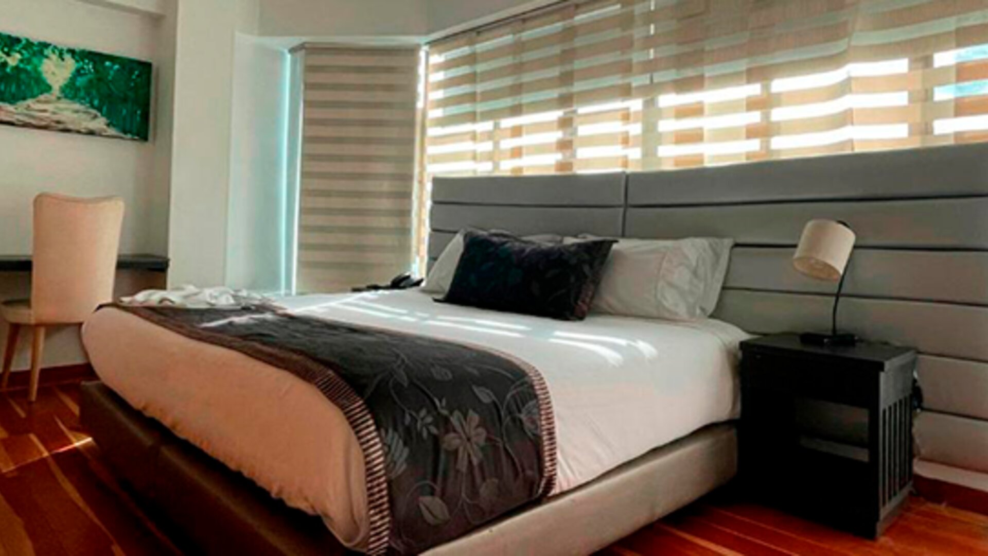 Modern guest room featuring a king bed, work desk, large windows and polished wood flooring at Hotel Airport Travel.