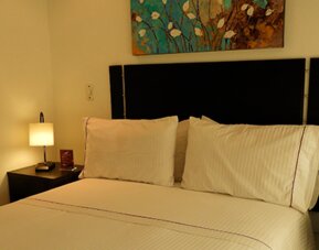 Cozy guest room featuring a double bed, bedside tables, floral arrangement and decorative wall art at Hotel Airport Travel.