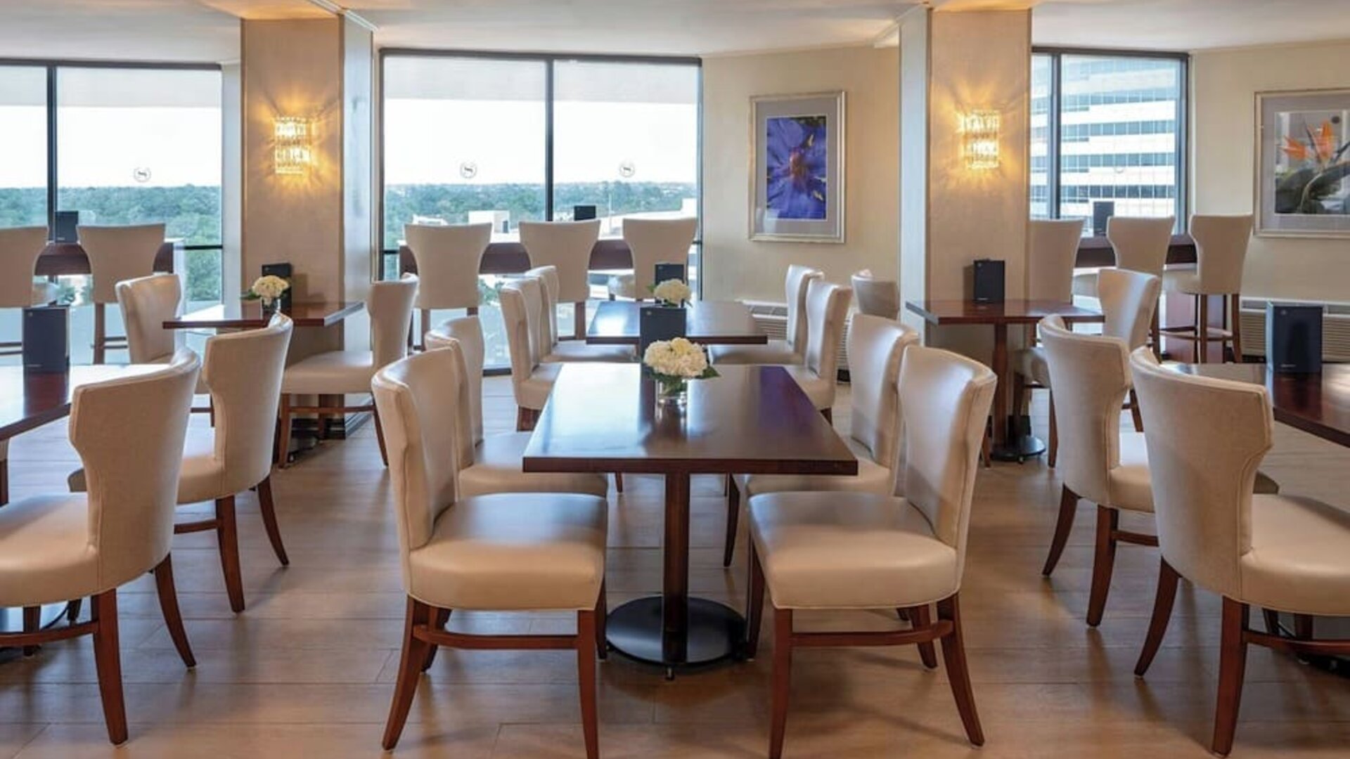 Bright dining area featuring floor-to-ceiling windows, upholstered seating and contemporary décor at Sheraton Houston Brookhollow Hotel.