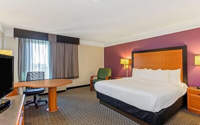 Contemporary guest room featuring a king-size bed, a spacious work area and modern furnishings at La Quinta Inn & Suites By Wyndham Orlando I Drive/Conv Ctr.