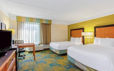Bright guest room featuring two double beds, a dedicated workspace and large windows with natural light at La Quinta Inn & Suites By Wyndham Orlando I Drive/Conv Ctr.