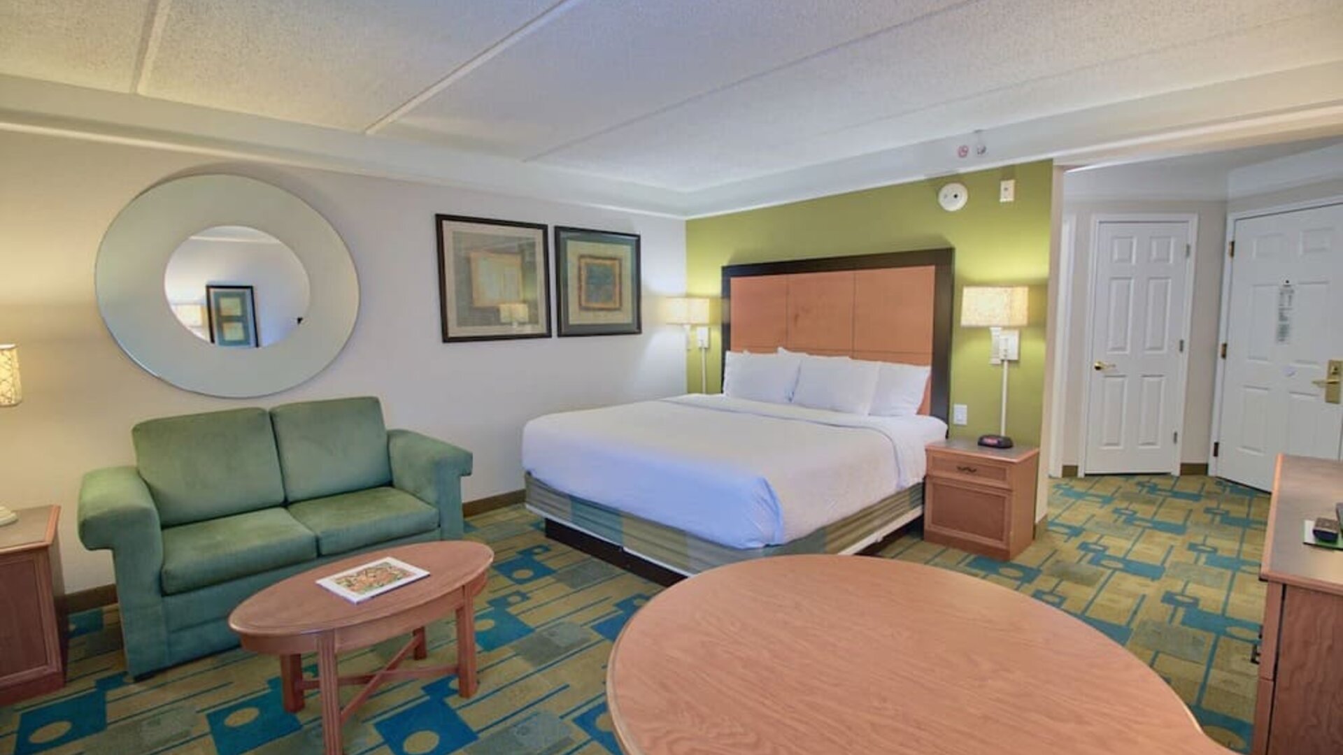 Comfortable suite featuring a king-size bed, a sofa seating area and an open-concept layout at La Quinta Inn & Suites By Wyndham Orlando I Drive/Conv Ctr.