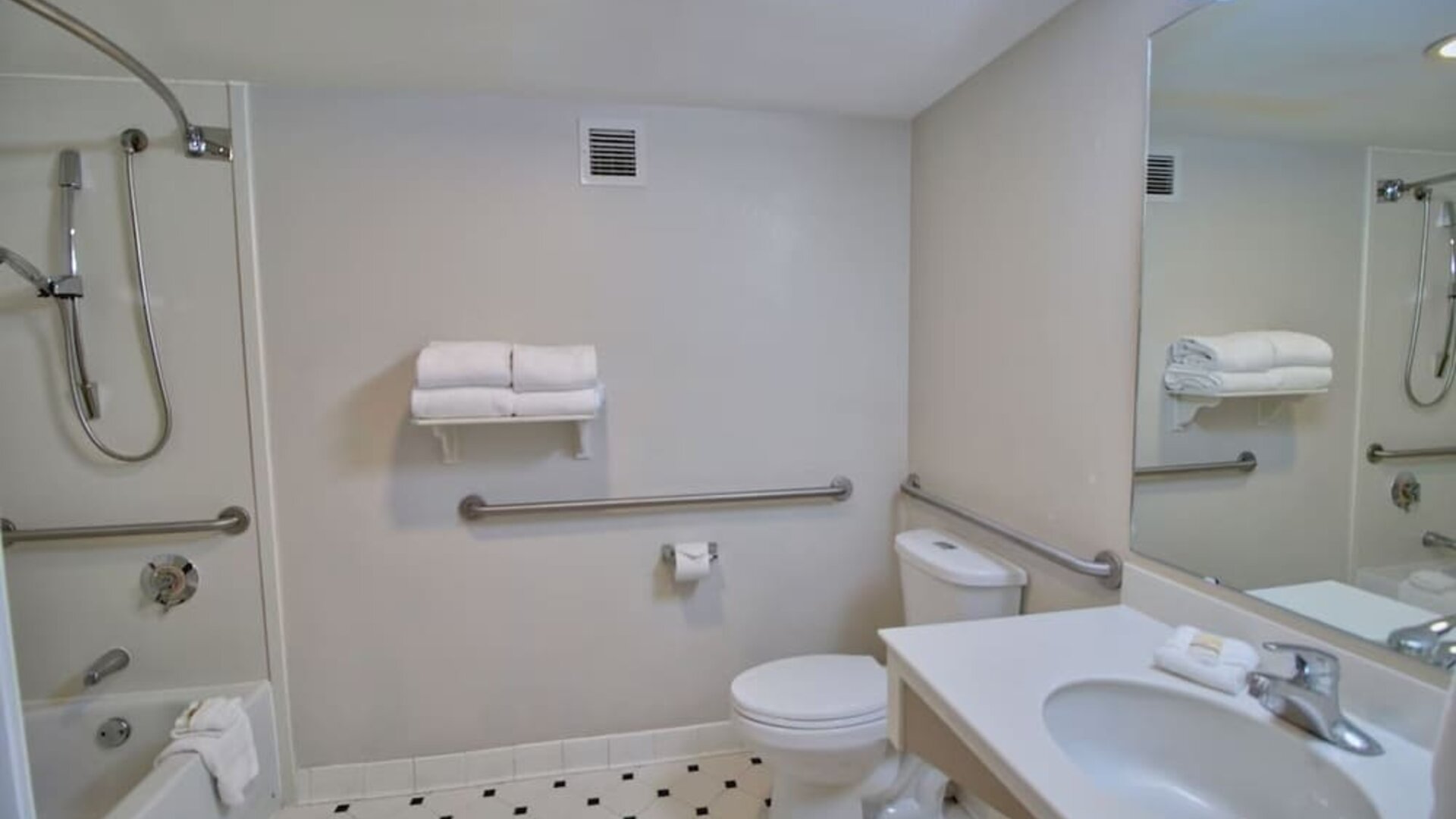 Accessible bathroom featuring safety grab bars, a spacious vanity and a combined shower and bathtub at La Quinta Inn & Suites By Wyndham Orlando I Drive/Conv Ctr.