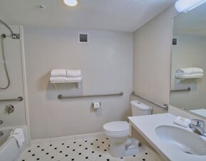 Accessible bathroom featuring safety grab bars, a spacious vanity and a combined shower and bathtub at La Quinta Inn & Suites By Wyndham Orlando I Drive/Conv Ctr.