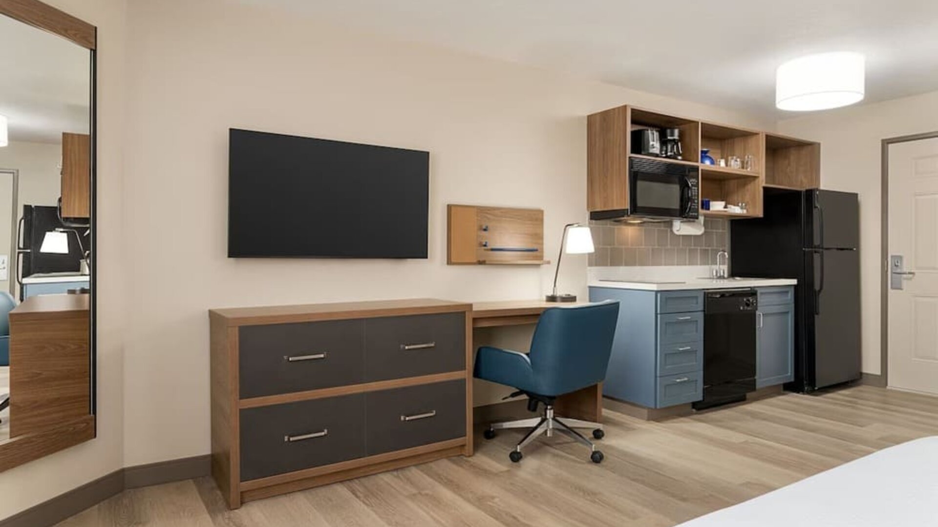 In-room workspace and kitchenette featuring a full-size refrigerator, microwave, dishwasher and dedicated desk area at Candlewood Suites Meridian.