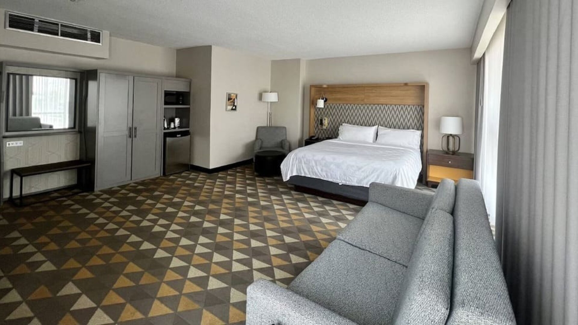 Spacious guest room featuring a king-size bed, comfortable seating, modern furnishings and ample living space at Holiday Inn Toronto Airport East.