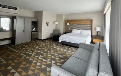 Spacious guest room featuring a king-size bed, comfortable seating, modern furnishings and ample living space at Holiday Inn Toronto Airport East.