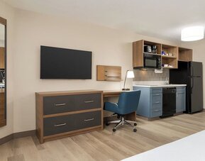 In-room workspace and kitchenette featuring a full-size refrigerator, cooktop, microwave and dedicated desk area at Candlewood Suites Boise.