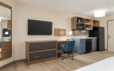 In-room workspace and kitchenette featuring a full-size refrigerator, cooktop, microwave and dedicated desk area at Candlewood Suites Boise.