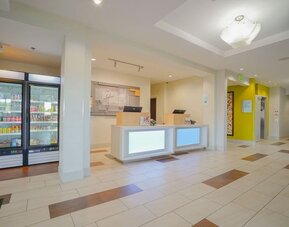 Reception area featuring a modern front desk, a grab-and-go market and bright, welcoming décor at Holiday Inn Express & Suites Ontario.