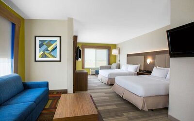 Spacious guest suite featuring two beds, a separate sitting area and contemporary furnishings at Holiday Inn Express & Suites Ontario.