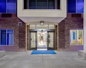 Hotel entrance featuring automatic sliding doors, covered access and contemporary exterior design at Holiday Inn Express & Suites Ontario.