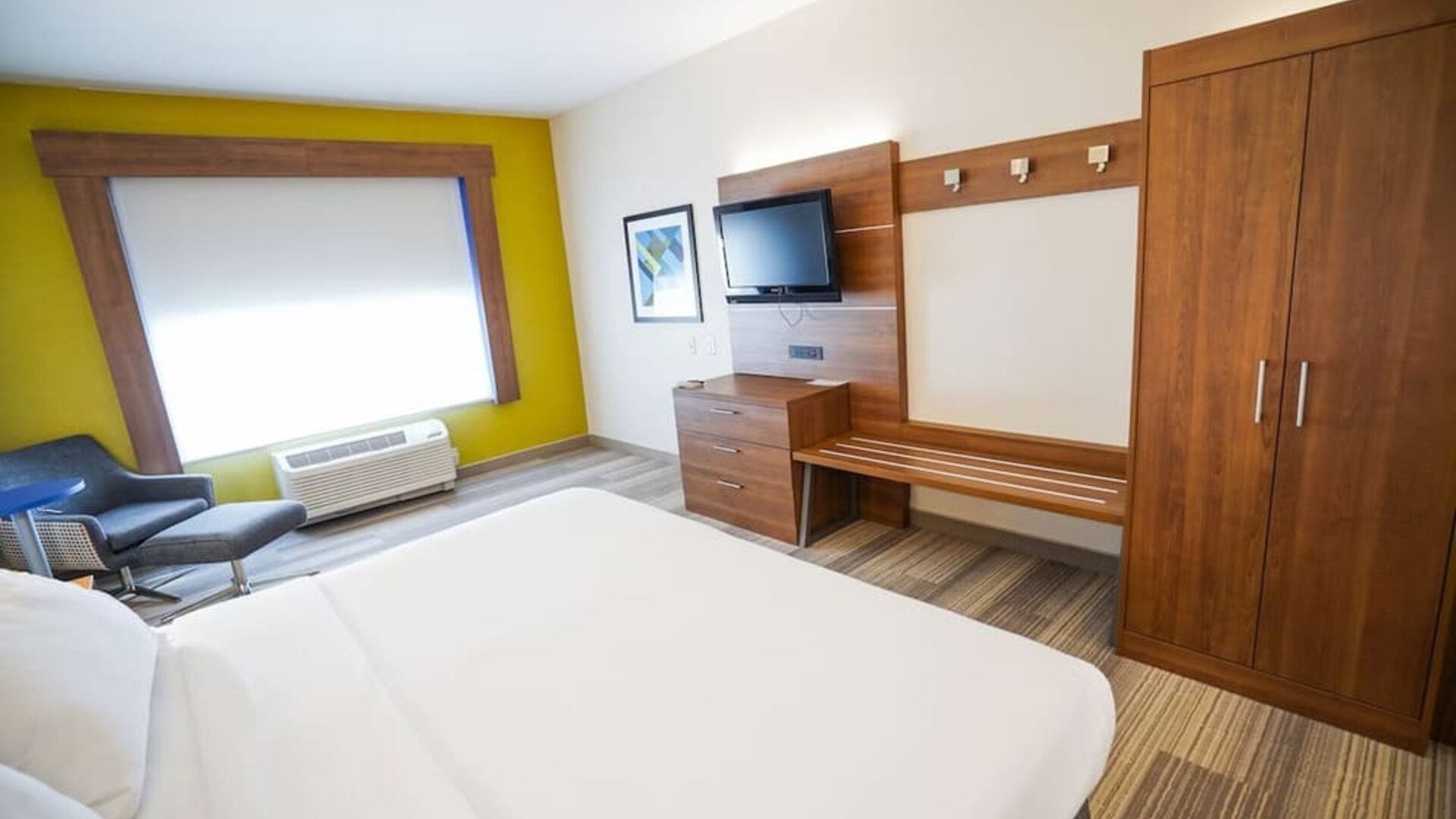 Guest room featuring a king-size bed, a large wardrobe, a dresser and comfortable seating at Holiday Inn Express & Suites Ontario.