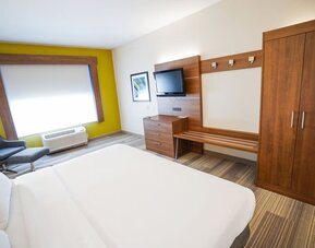 Guest room featuring a king-size bed, a large wardrobe, a dresser and comfortable seating at Holiday Inn Express & Suites Ontario.