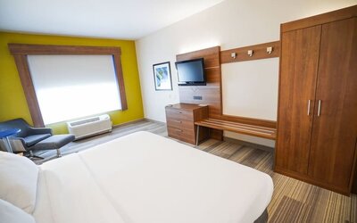 Guest room featuring a king-size bed, a large wardrobe, a dresser and comfortable seating at Holiday Inn Express & Suites Ontario.