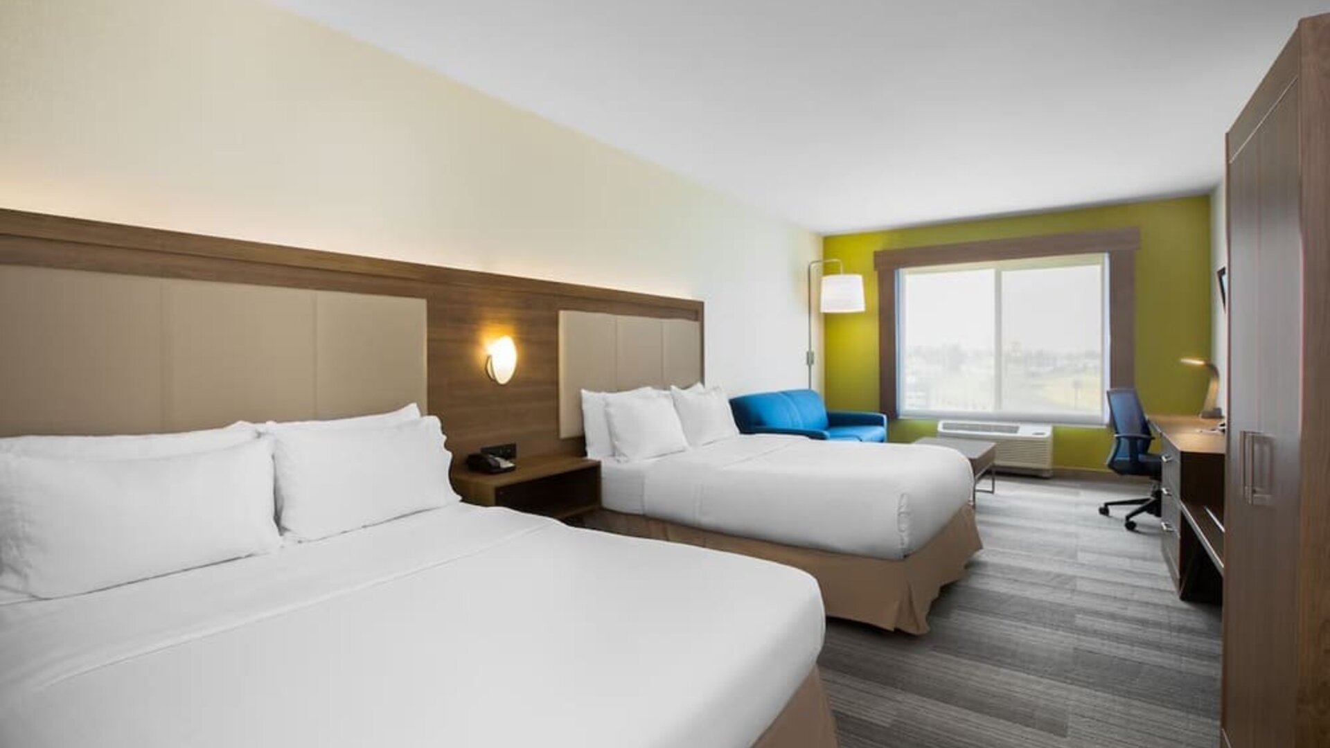Guest room featuring two beds, a comfortable sofa, a dedicated workspace and modern amenities at Holiday Inn Express & Suites Ontario.