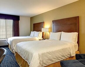 Guest room featuring two beds, a comfortable seating area and modern amenities designed for relaxation at Holiday Inn Express SFO Airport North.