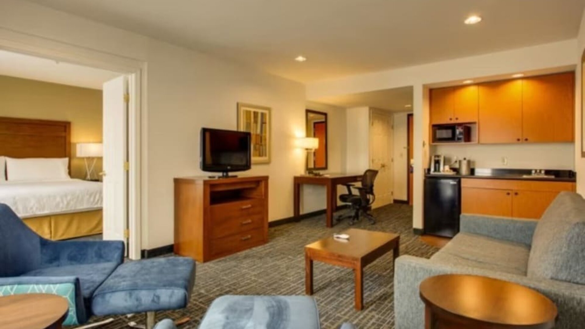 One-bedroom suite featuring a separate bedroom, a living area, a kitchenette and comfortable seating at Holiday Inn Express SFO Airport North.