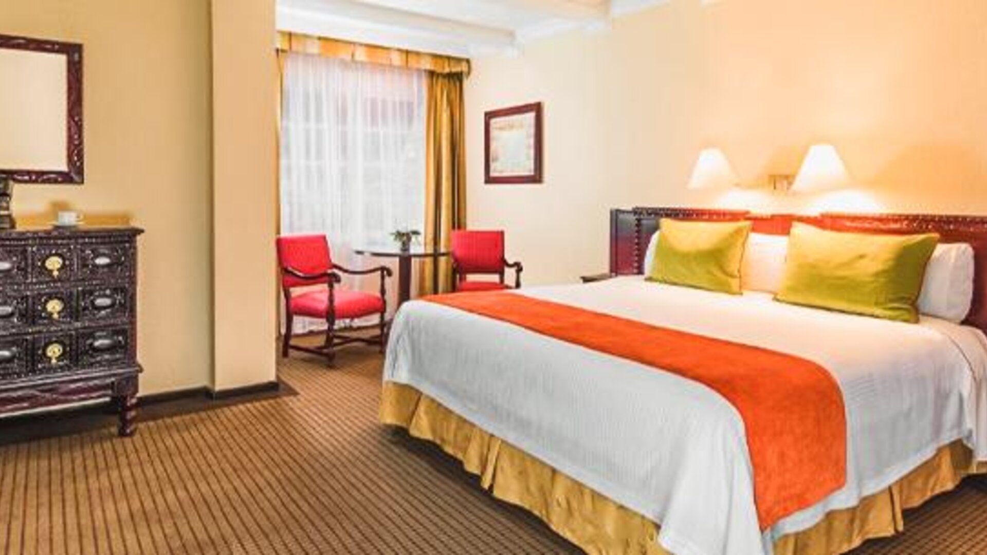 Guest room with one bed featuring handcrafted wood furniture, accent seating, bedside lamps, and classic interior design at Hotel Geneve.