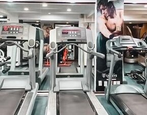 Fitness center equipped with treadmills, elliptical machines, cardio equipment, mirrors, and exercise stations at Hotel Geneve.