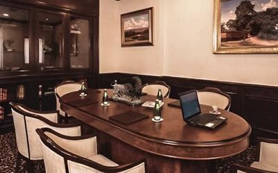 Executive boardroom featuring a large conference table, upholstered chairs, wood cabinetry, and workspace amenities at Hotel Geneve.