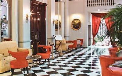 Elegant lobby featuring black-and-white tiled flooring, high ceilings, comfortable seating, and dramatic red drapery at Hotel Geneve.