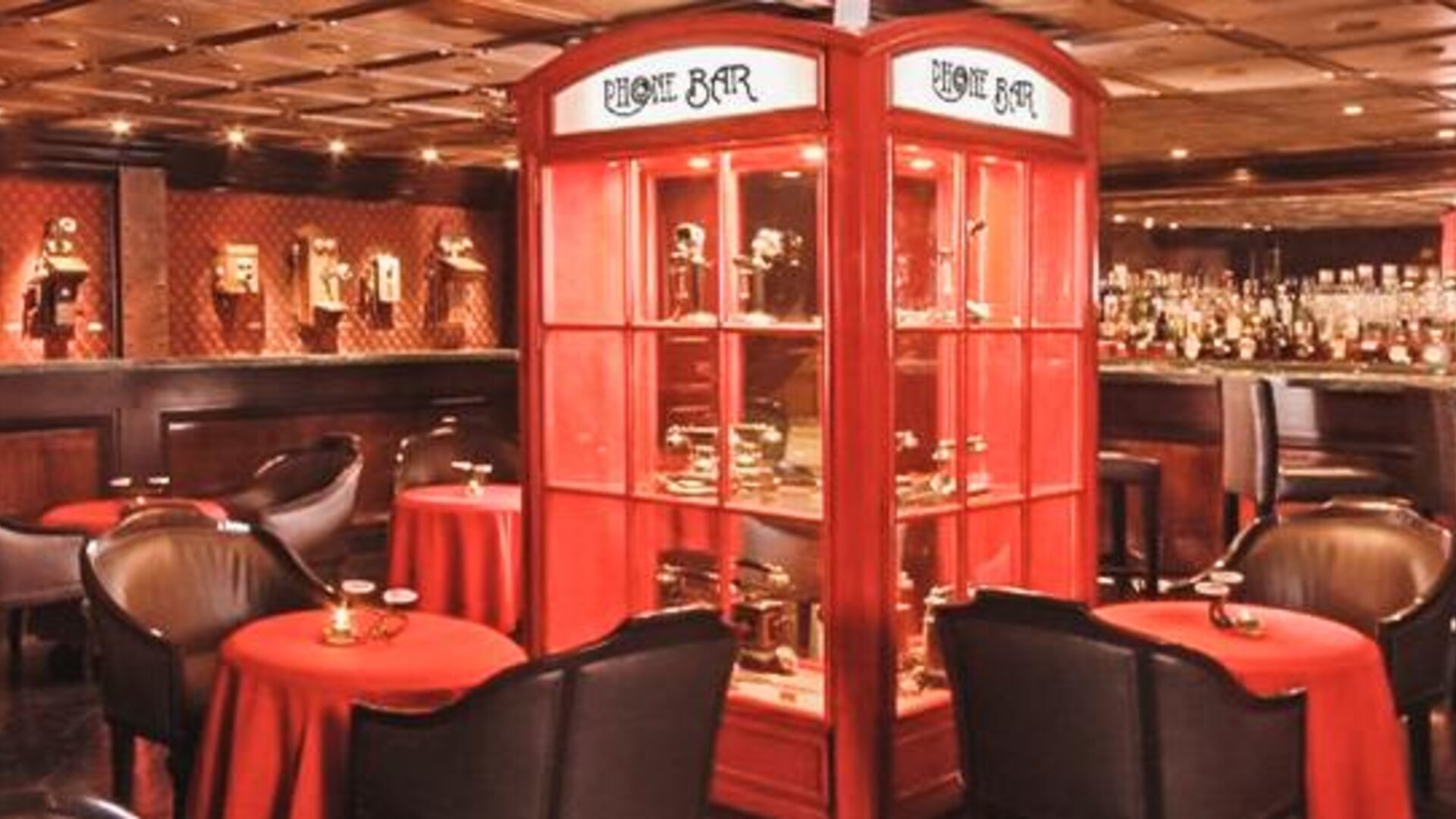 Piano bar featuring intimate table seating, decorative display cabinets, a fully stocked bar, and warm ambient lighting at Hotel Geneve.