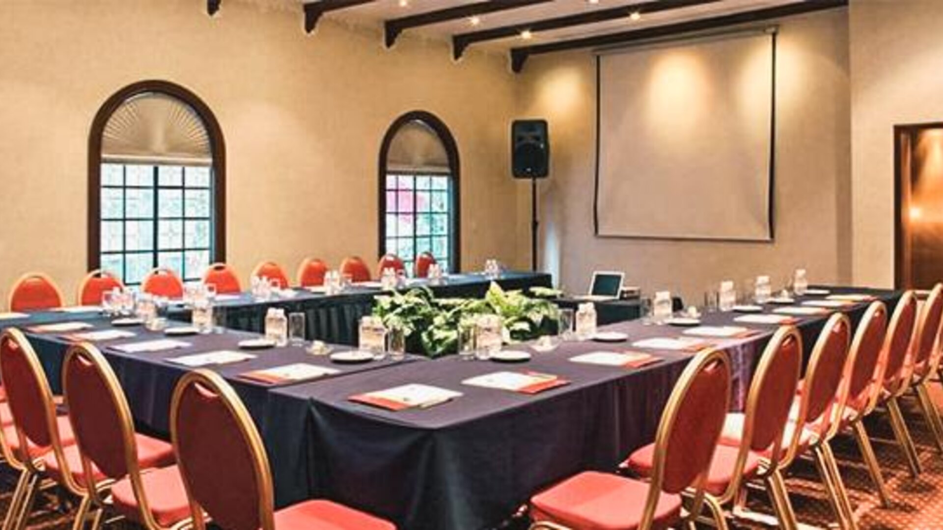 Meeting room arranged in a U-shaped conference layout with presentation equipment and banquet seating at Hotel Geneve.