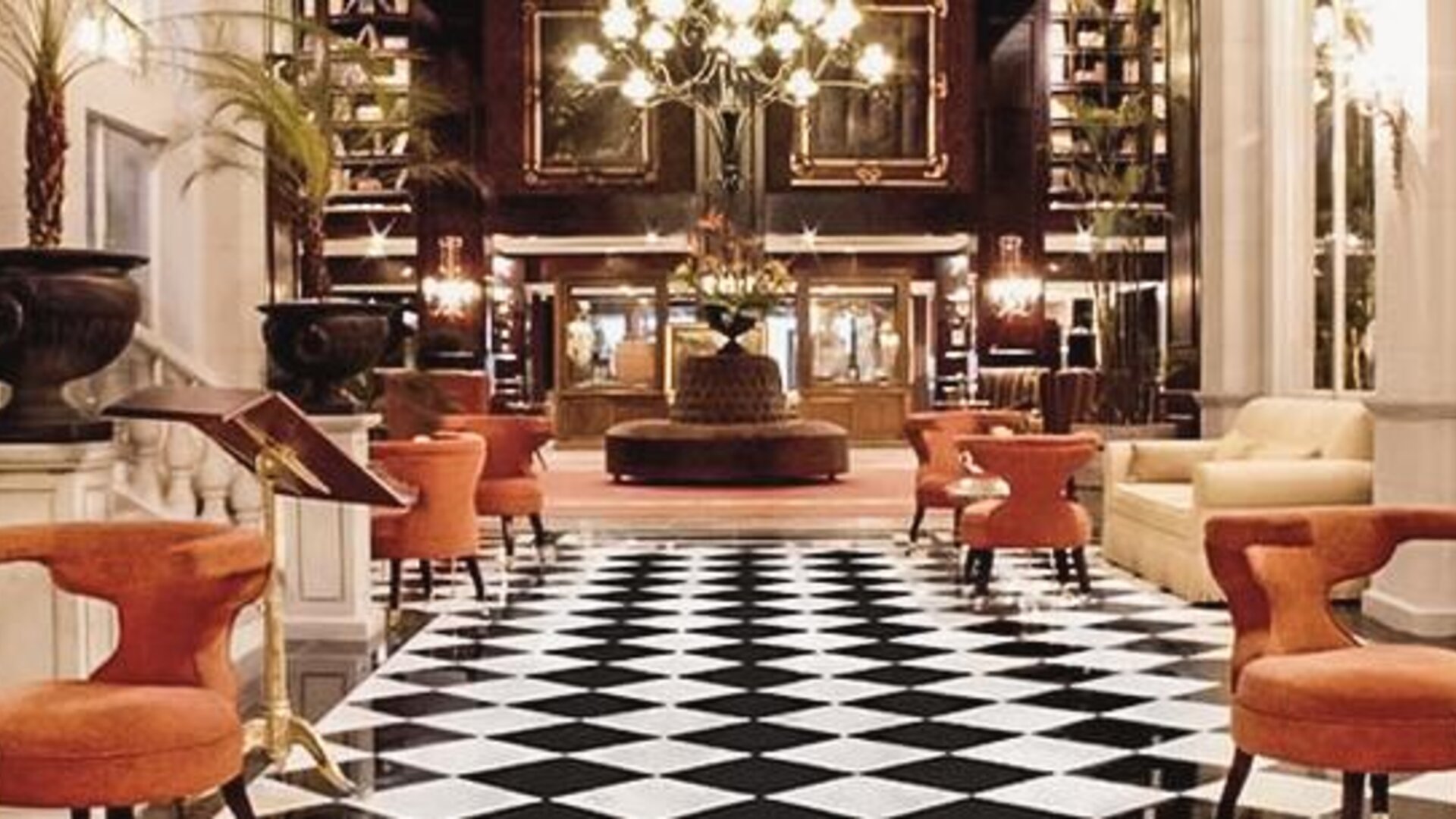 Elegant lobby with black-and-white tiled flooring, chandeliers, plush seating, and a grand entrance at Hotel Geneve.