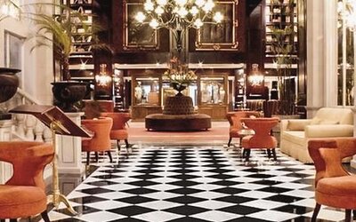 Elegant lobby with black-and-white tiled flooring, chandeliers, plush seating, and a grand entrance at Hotel Geneve.