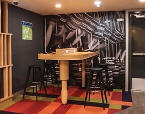 Casual dining area with communal tables, contemporary seating, geometric décor, and an open layout at Ibis Styles Mexico Reforma.