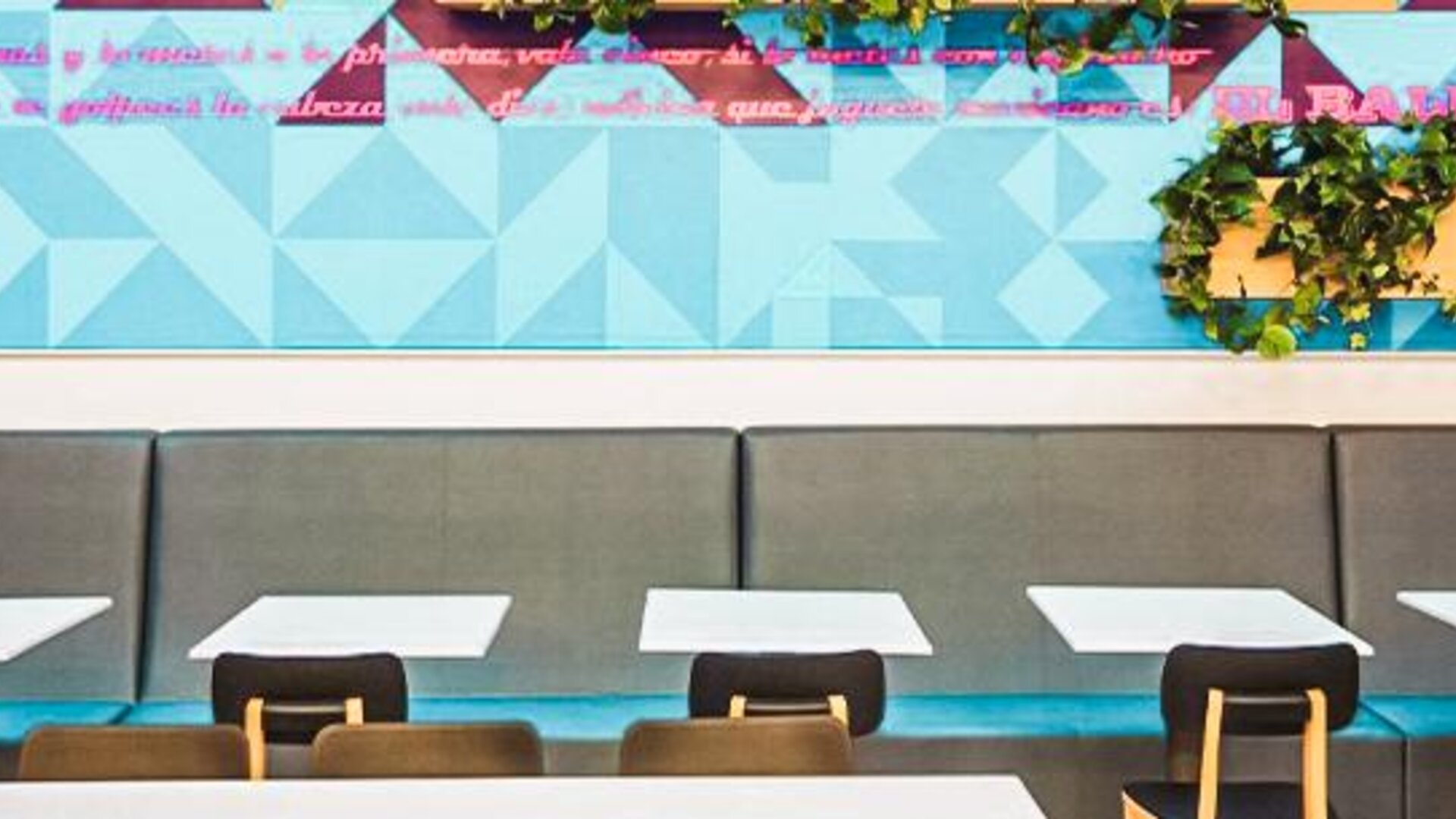 Dining area with booth seating, geometric wall art, decorative greenery, and contemporary furnishings at Ibis Styles Mexico Reforma.