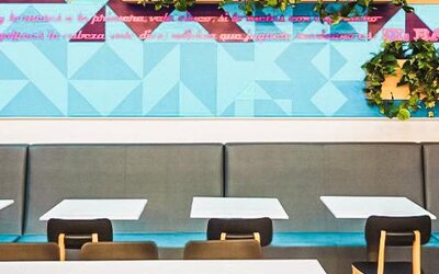 Dining area with booth seating, geometric wall art, decorative greenery, and contemporary furnishings at Ibis Styles Mexico Reforma.