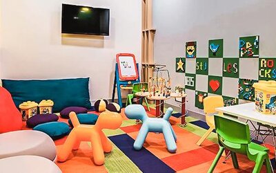 Children's play area featuring toys, activity tables, colorful seating, and entertainment options at Ibis Styles Mexico Reforma.