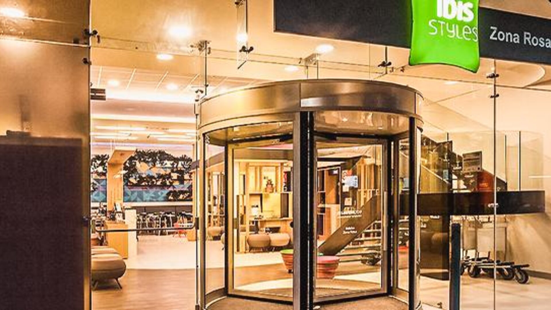 Glass entrance with revolving doors, contemporary lighting, and a welcoming reception area at Ibis Styles Mexico Reforma.