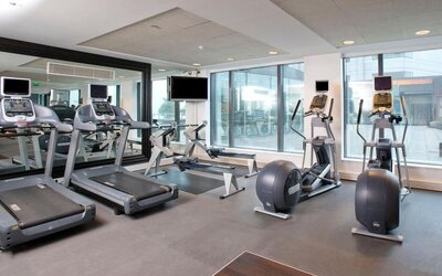 Hotel fitness center with treadmills, rowing machines, elliptical trainers, exercise bikes, mirrors and large windows.