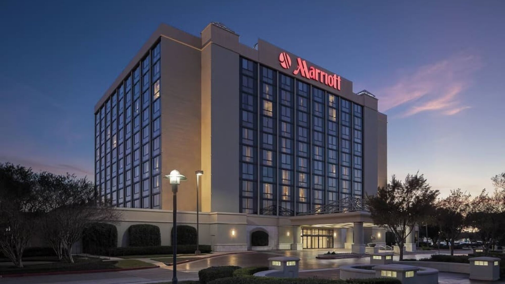 Exterior view showcasing the hotel's contemporary architecture, landscaped grounds, and covered entrance at Houston Marriott South at Hobby Airport.