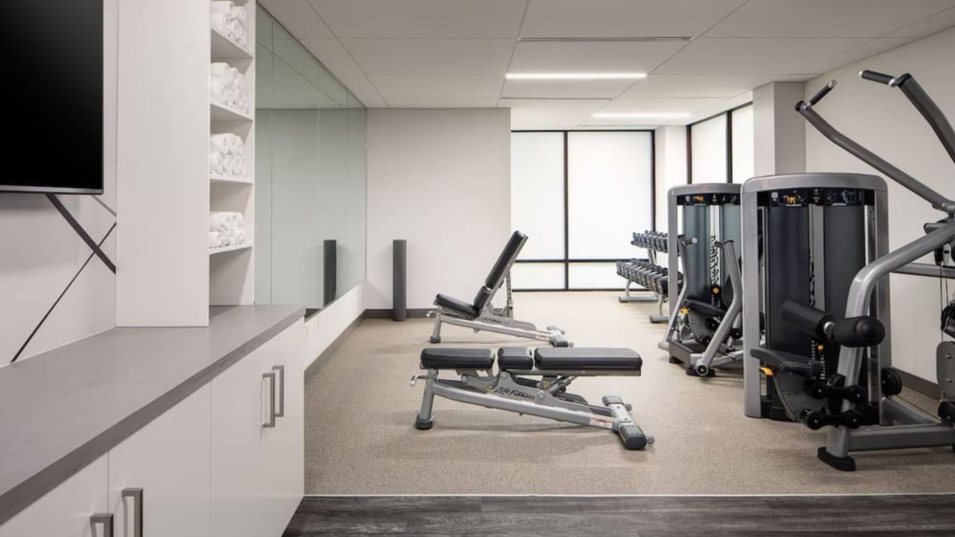 Fitness center featuring strength-training equipment, free weights, and a bright, modern workout space at Houston Marriott South at Hobby Airport.