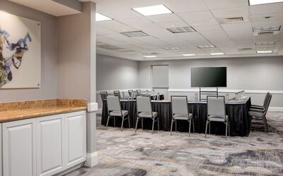 Meeting facility featuring a collaborative seating arrangement, presentation screen, and flexible event space at Houston Marriott South at Hobby Airport.