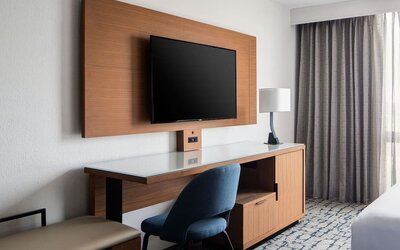 In-room workspace featuring a spacious desk, mounted television, and ergonomic seating at Houston Marriott South at Hobby Airport.