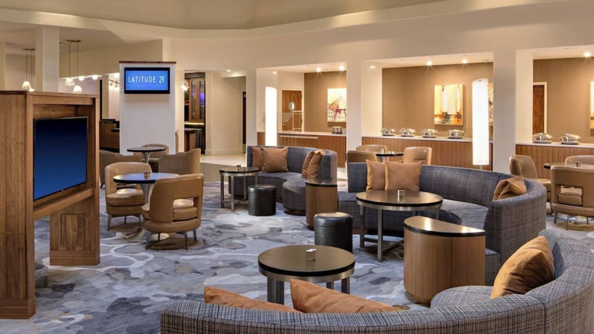 Lobby area featuring comfortable seating, gathering spaces, and access to dining amenities at Houston Marriott South at Hobby Airport.