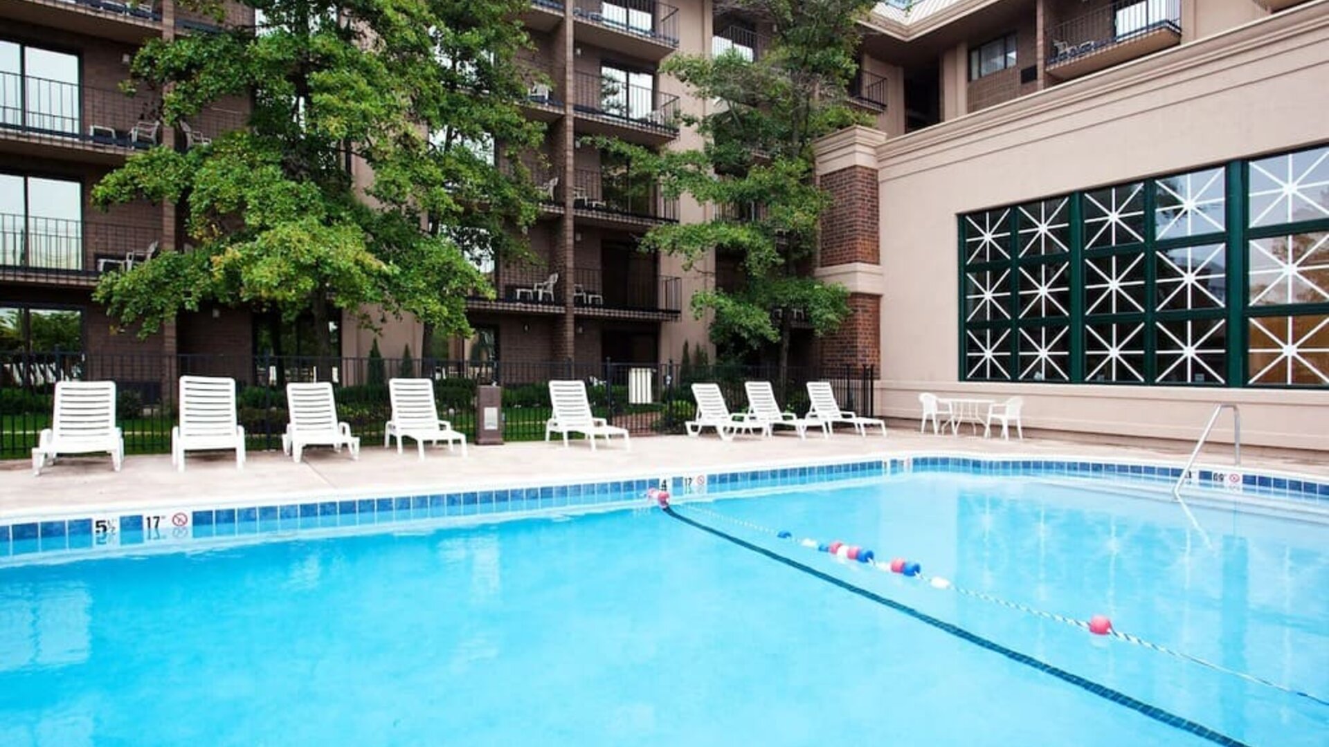 Outdoor swimming pool featuring lounge chairs, landscaped surroundings, and guest accommodations overlooking the pool area at Holiday Inn Express Rolling Meadows-Schaumburg.