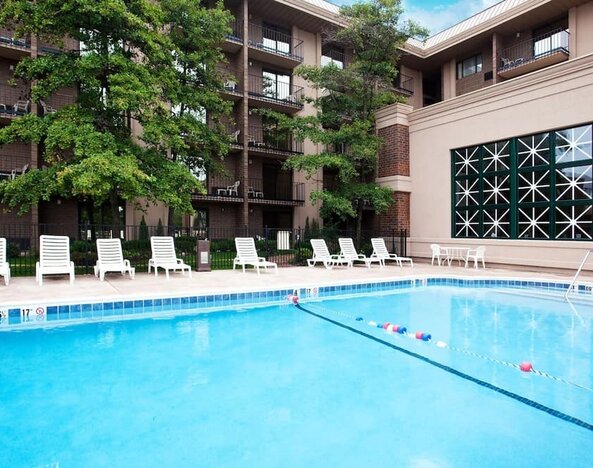 Outdoor swimming pool featuring lounge chairs, landscaped surroundings, and guest accommodations overlooking the pool area at Holiday Inn Express Rolling Meadows-Schaumburg.