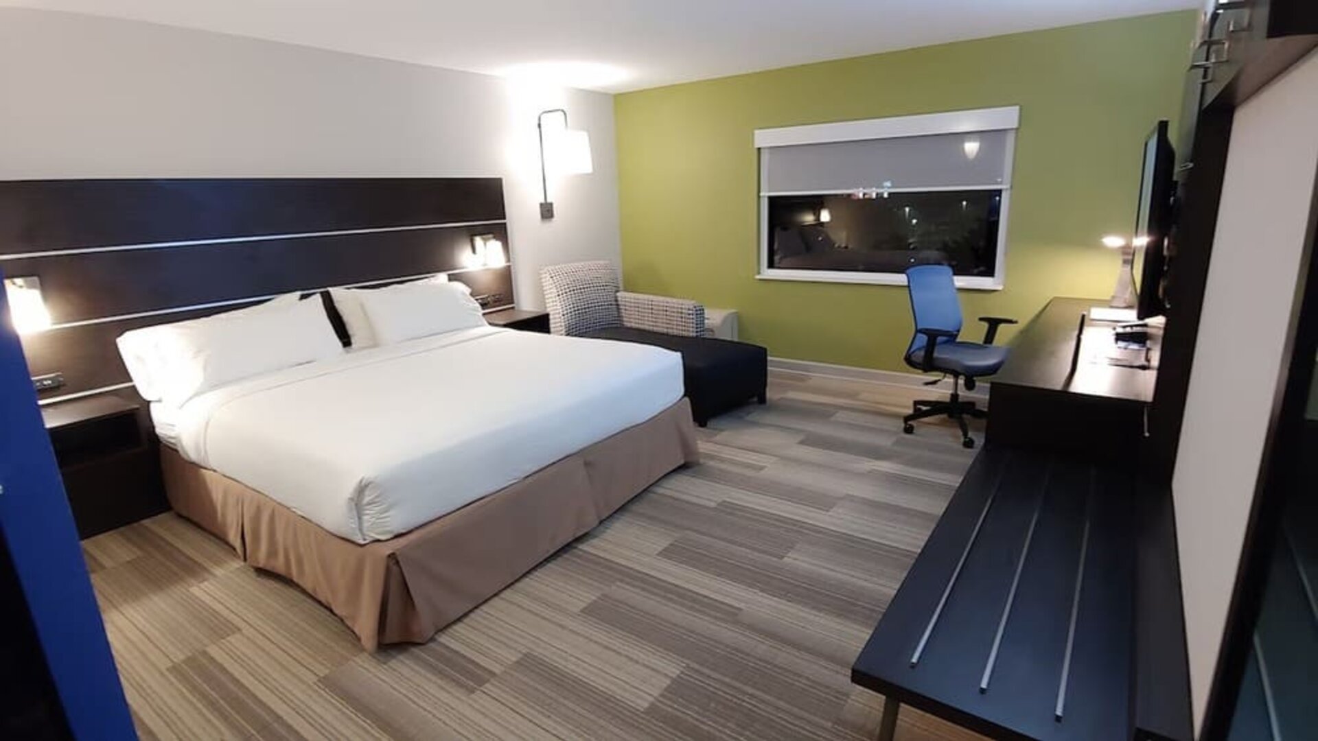Guest room featuring a king bed, an upholstered chair, a dedicated workspace, and contemporary furnishings at Holiday Inn Express Rolling Meadows-Schaumburg.